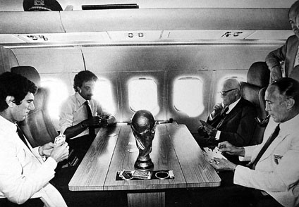 Il Presidente della Repubblica Sandro Pertini con Zoff, Causio e Bearzot sul DC9 militare che li sta riportando da Madrid a Roma. Sul tavolo la coppa del Mundial, 12 luglio 1982.