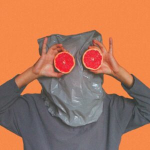 person covered with plastic bag on head while holding sliced blood orange