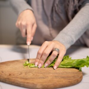 crop housewife cutting fresh salad in kitchen