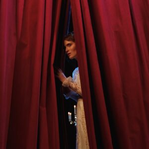 woman standing behind red curtain
