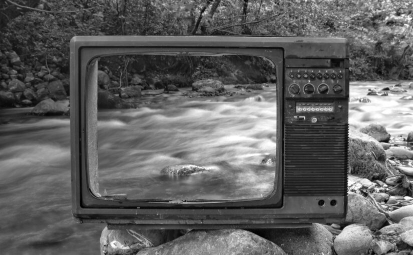retro tv on river shore near forest