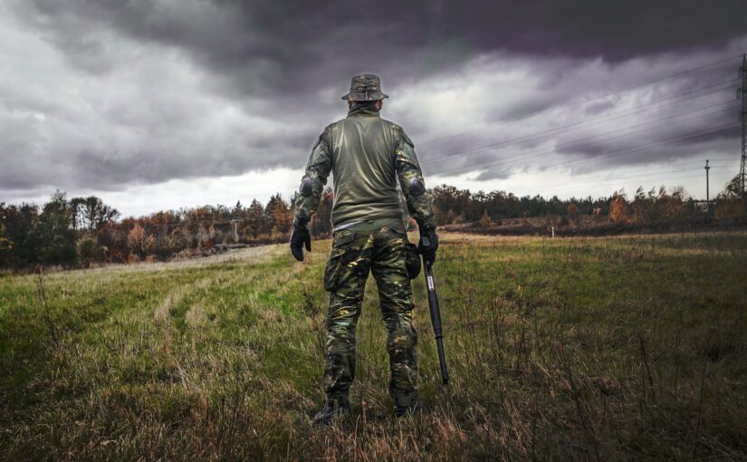 man in camouflage suit holding shotgun
