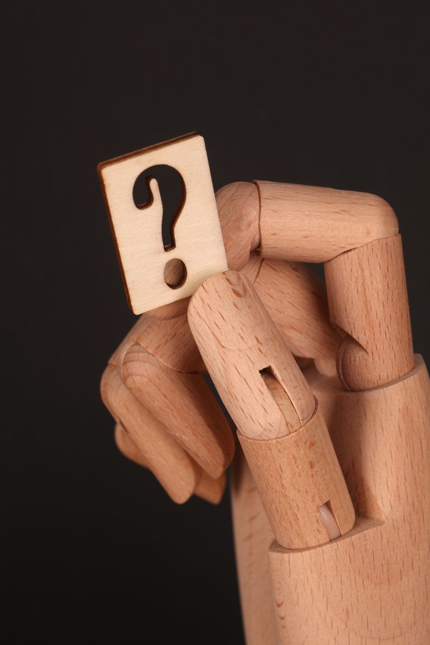 wooden hand holding question mark